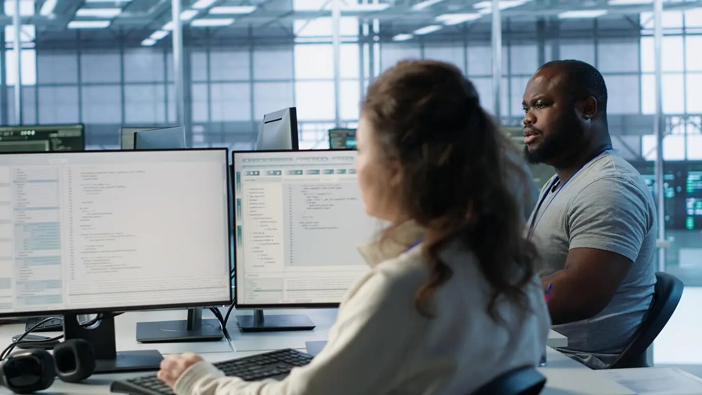 An engineer and colleagues overseeing server room infrastructure components.